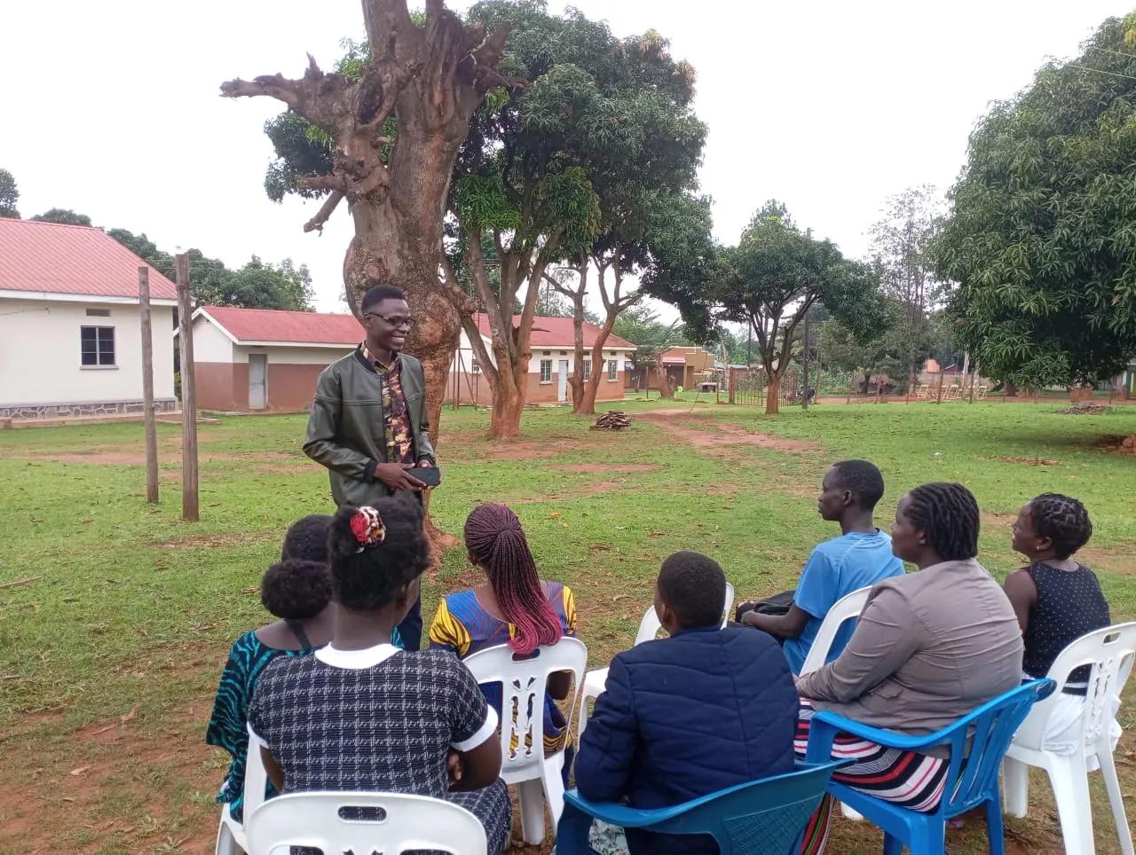 CAR evangelist teaching a seated community group outdoors under a large tree